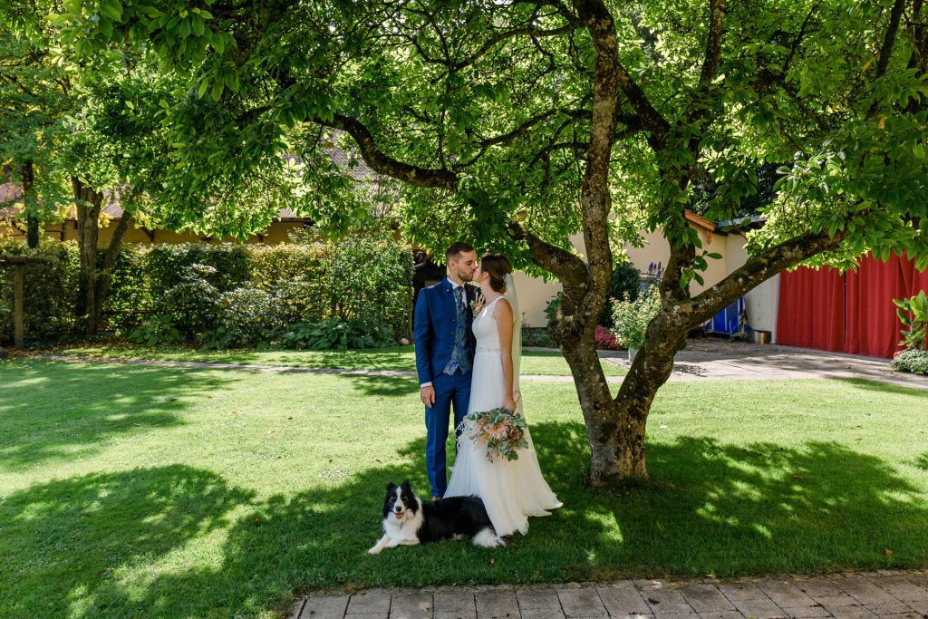Entspannte Hochzeitsfotografie im Garten der Hochzeitslocation mit Hund