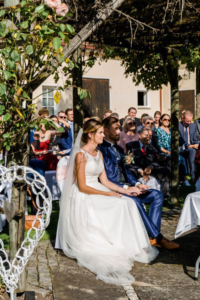 Hochzeitsfotografin Christina Klass, Freie Trauung, Brautpaar mit Gästen im Hintergrund