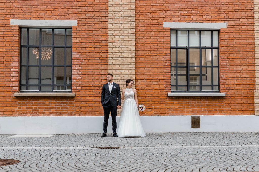 Hochzeitsfotos, Brautpaarbild an einem Backsteingebäude, Brautpaarshooting beim Nuno in Augsburg, Brautpaarfotos, Hochzeitsfotografie Augsburg, modernes Brautpaar, heiraten im Nuno Augsburg